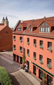 ein orangefarbenes Gebäude mit Blumenkästen an den Fenstern in der Unterkunft Hotel-Pension Am Schwanenteich in Lutherstadt Wittenberg