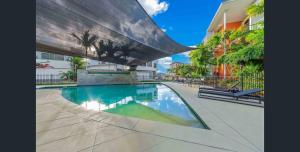 a swimming pool in front of a building at Peninsula Airlie Beach in Airlie Beach