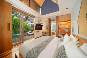 a bedroom with a large white bed and a tv at Sanora Villa Sanur by Ini Vie Hospitality in Sanur