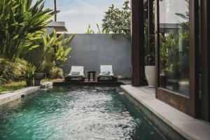 a pool in a backyard with two chairs and a table at Sanora Villa Sanur by Ini Vie Hospitality in Sanur