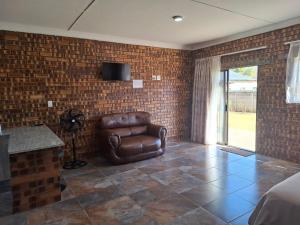 a bedroom with a leather chair in a brick wall at Mitchell Manor in Vryheid