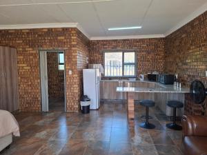 a kitchen with a white refrigerator and a brick wall at Mitchell Manor in Vryheid