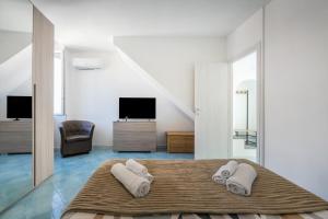 a white bedroom with a bed with two towels at La casa del Pescatore in Procida