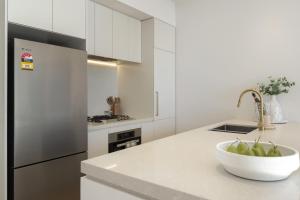 a white kitchen with a bowl of apples on a counter at Azure Horizon - Bay Views & Rooftop Spa in Frankston