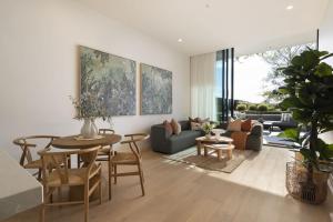 a living room with a table and a couch at Azure Horizon - Bay Views & Rooftop Spa in Frankston