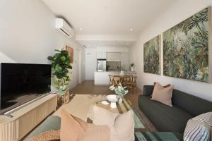 a living room with a couch and a tv at Azure Horizon - Bay Views & Rooftop Spa in Frankston +8 photos