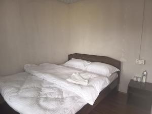 a bed with white sheets and a hat on it at hotel lakema in Pokhara