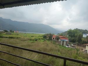 a view from a fence of a field and a mountain at hotel lakema in Pokhara
