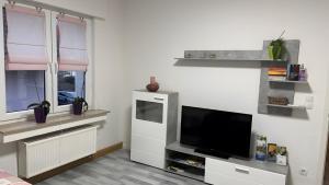 a living room with a flat screen tv and windows at Ferienwohnung auf dem Traumpfad in Ettringen