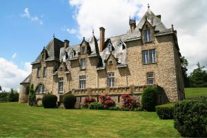 an old stone house with red flowers in the yard at La Sicorie in Saint-Germain-le-Guillaume