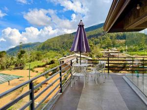 a balcony with a table and chairs and an umbrella at Nicholas Cottage in Nuwara Eliya