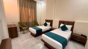 a hotel room with two beds and a chair at Hotel Harsh Vilas-Near Tajmahal Agra in Agra +42 photos