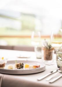 a plate of food on a table with a glass of wine at Miraval NaturHotel in Badia