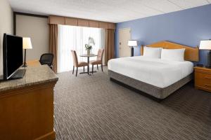 a hotel room with a bed and a desk with a television at Days Hotel by Wyndham Toms River Jersey Shore in Toms River