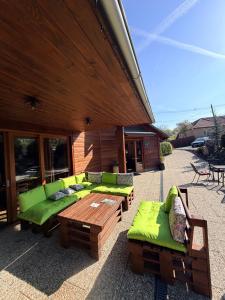 a patio with green couches and a wooden building at Penzión u Coľa in Prievidza