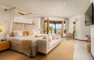 a bedroom with a large bed and a balcony at Acajou Beach Resort in Baie Sainte Anne