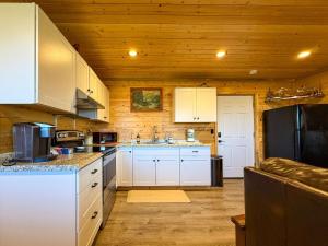a kitchen with white cabinets and a black refrigerator at Cozy Pine Getaway in Sequim