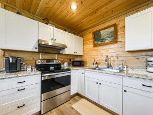 a kitchen with white cabinets and a stove at Cozy Pine Getaway in Sequim