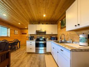 a kitchen with white cabinets and a wooden ceiling at Cozy Pine Getaway in Sequim