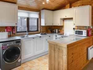 a kitchen with white cabinets and a washer and sink at Burnside Park in Keswick