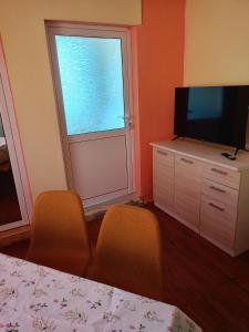 a bedroom with a television and two chairs and a window at Pretty house in Panagyurishte