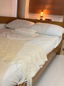 a bed with white sheets and pillows on it at Spacious Bunk Bed & Dedicated Workspace in Baler