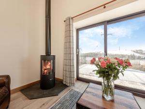 a living room with a fireplace and a vase of flowers at Parlwr Godro - Uk41513 in Llanfair Clydogau