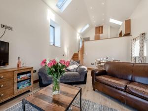 a living room with a couch and a vase of flowers on a table at Parlwr Godro - Uk41513 in Llanfair Clydogau