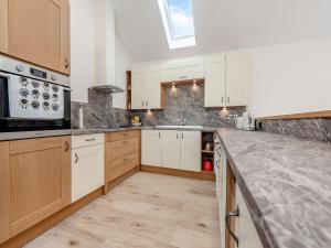 a kitchen with white cabinets and a counter top at Parlwr Godro - Uk41513 in Llanfair Clydogau +10 photos