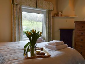 a bed with a vase of flowers and towels on it at Puzzle Corner in Sandsend
