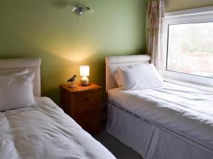 a bedroom with two beds and a lamp on a night stand at Puzzle Corner in Sandsend