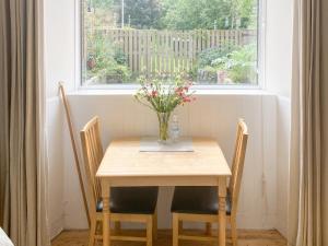 a table and chairs with a vase of flowers on it at The Wee Cottage - Uk42919 in Dunfermline