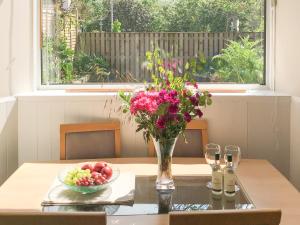 a table with a vase of flowers and a bowl of fruit at The Wee Cottage - Uk42919 in Dunfermline