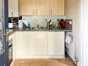 a kitchen with white cabinets and a sink at The Wee Cottage - Uk42919 in Dunfermline
