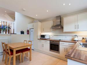 a kitchen with white cabinets and a wooden table at Oakridge in Salcombe