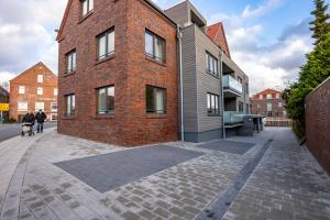 a brick building on a street with people walking past it at Nr 301 - Apartmenthaus "Harleblick" in Carolinensiel