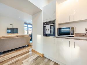 a kitchen with white cabinets and a microwave at Ty Gwair - Uk41512 in Lampeter