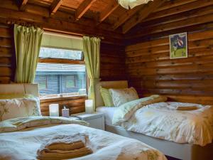 a bedroom with two beds in a log cabin at Forest View in Strathyre +5 photos