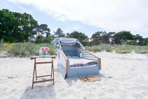 a bed sitting on the beach next to a table at Schlafstrandkorb Nr 8 in Timmendorfer Strand