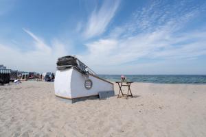 a small boat on the beach with a table at Schlafstrandkorb Nr 8 in Timmendorfer Strand +4 photos