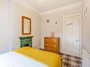 a bedroom with a bed and a mirror and a dresser at Gardeners Cottage in Huntly