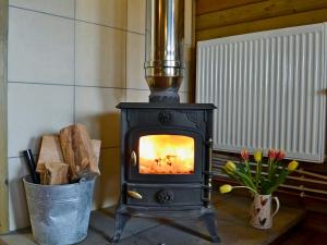 a stove in a room with a bucket of wood at Kestrel Cabin - Uk1246 in Westward