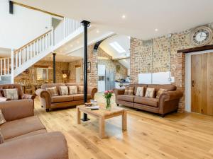a living room with couches and a clock on the wall at Pipistrelle Barn in North Walsham