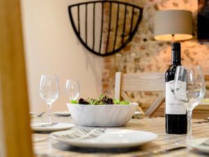 a table with a bowl of salad and a bottle of wine at Pipistrelle Barn in North Walsham