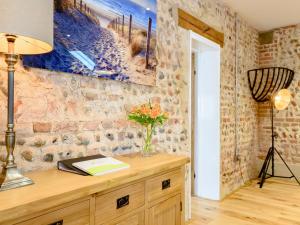 a desk with a vase of flowers on a brick wall at Pipistrelle Barn in North Walsham +23 photos