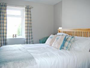 a bedroom with a white bed with pillows and a window at Summergate Cottage in Annan