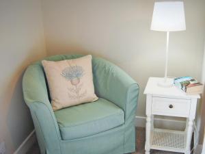 a green chair with a pillow sitting next to a table at Summergate Cottage in Annan +6 photos