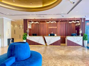 a lobby with a blue chair in front of a counter at Donatello Hotel in Dubai +65 photos