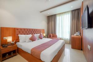 a hotel room with a large bed and a television at Hotel Tranquil Airport Road Sector 66 Mohali Chandigarh in Mohali