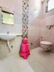 a bathroom with a pink toilet and a sink at Sai Tara Residency in Shirdi